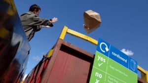 Man throwing cardboard box into bin